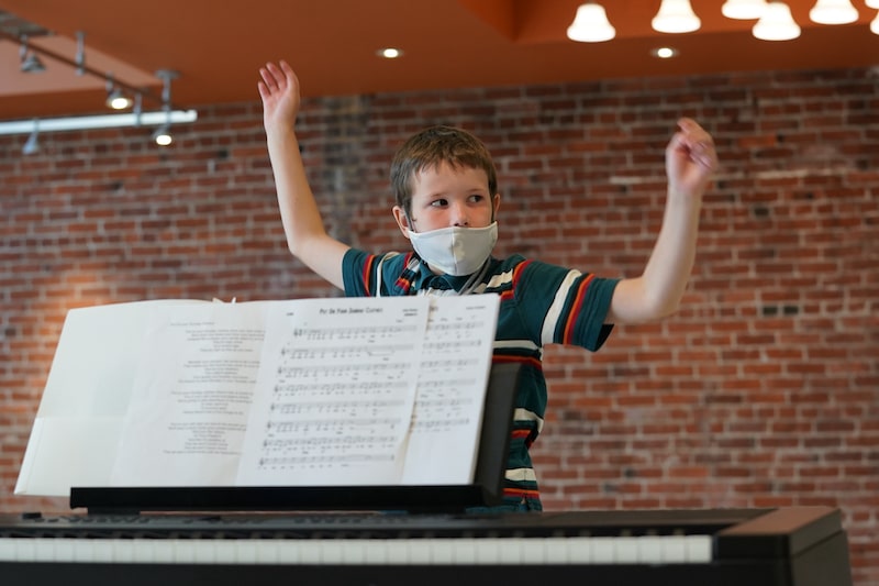 young boy dancing in front of a piano