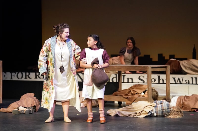 Miss Hannigan punishing Annie who has a bag in her hand